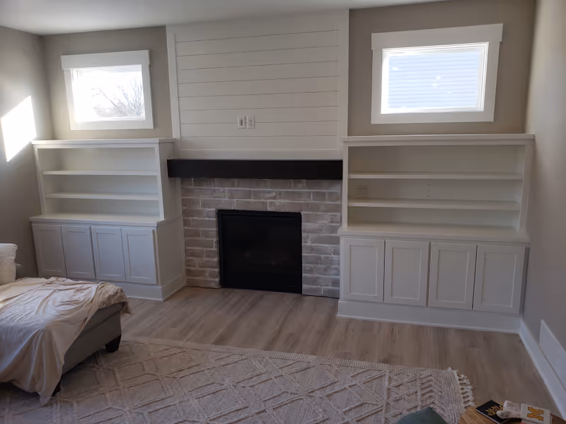 Fireplace built-ins with white cabinets, shiplap detail, and stone surround