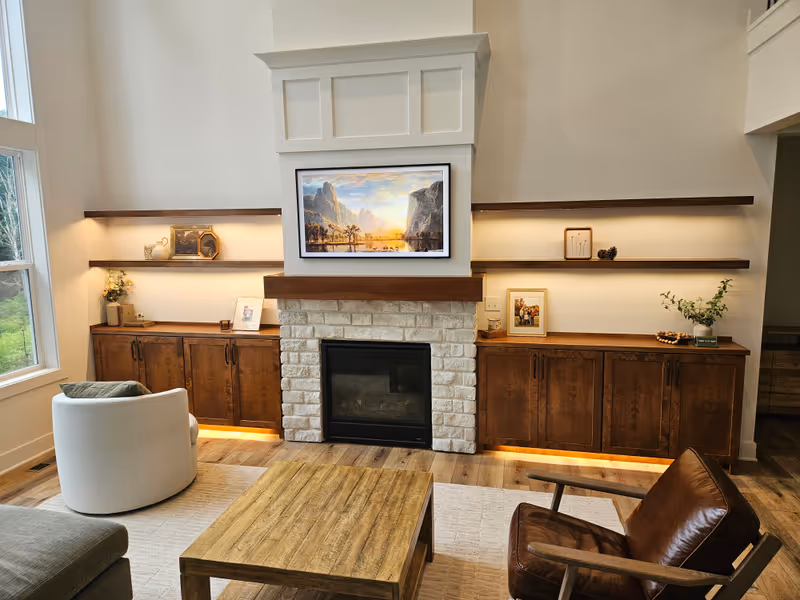 Custom built-in cabinets with walnut shelves, stone fireplace surround, and LED accent lighting — built by Dan Brink