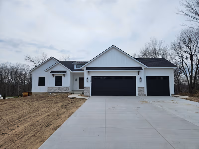 Custom-built modern farmhouse — board-and-batten siding, stone wainscot, and black metal roof accents — built by Dan Brink